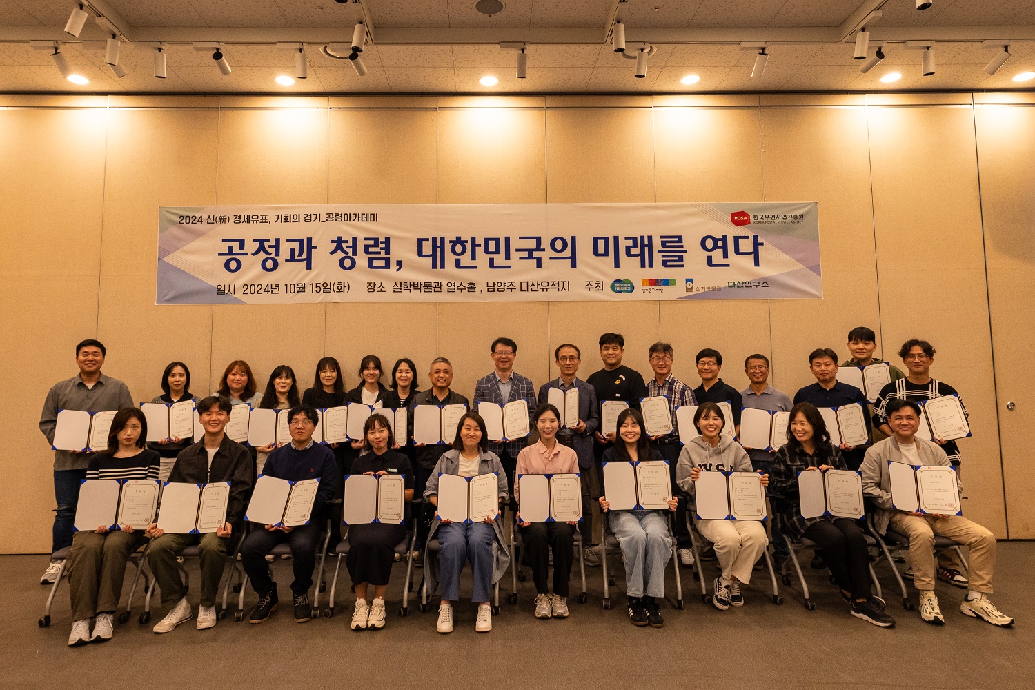 감사관계자 청렴 워크숍 수료증을 펼쳐 앞줄에는 앉아서 뒷줄은 서서 기념촬영 중인 모습