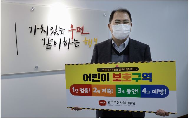 가치있는 우편 / 같이하는 행복 / 어린이 교통안전 릴레이 챌린지 / 어린이 보호구역 / 1단 멈춤! 2쪽 저쪽! 3초 동안! 4고 예방! / POSA 한국우편사업진흥원 / 한국우편사업진흥원, 어린이 교통안전 릴레이 캠페인 동참하며 사진을 찍는 모습