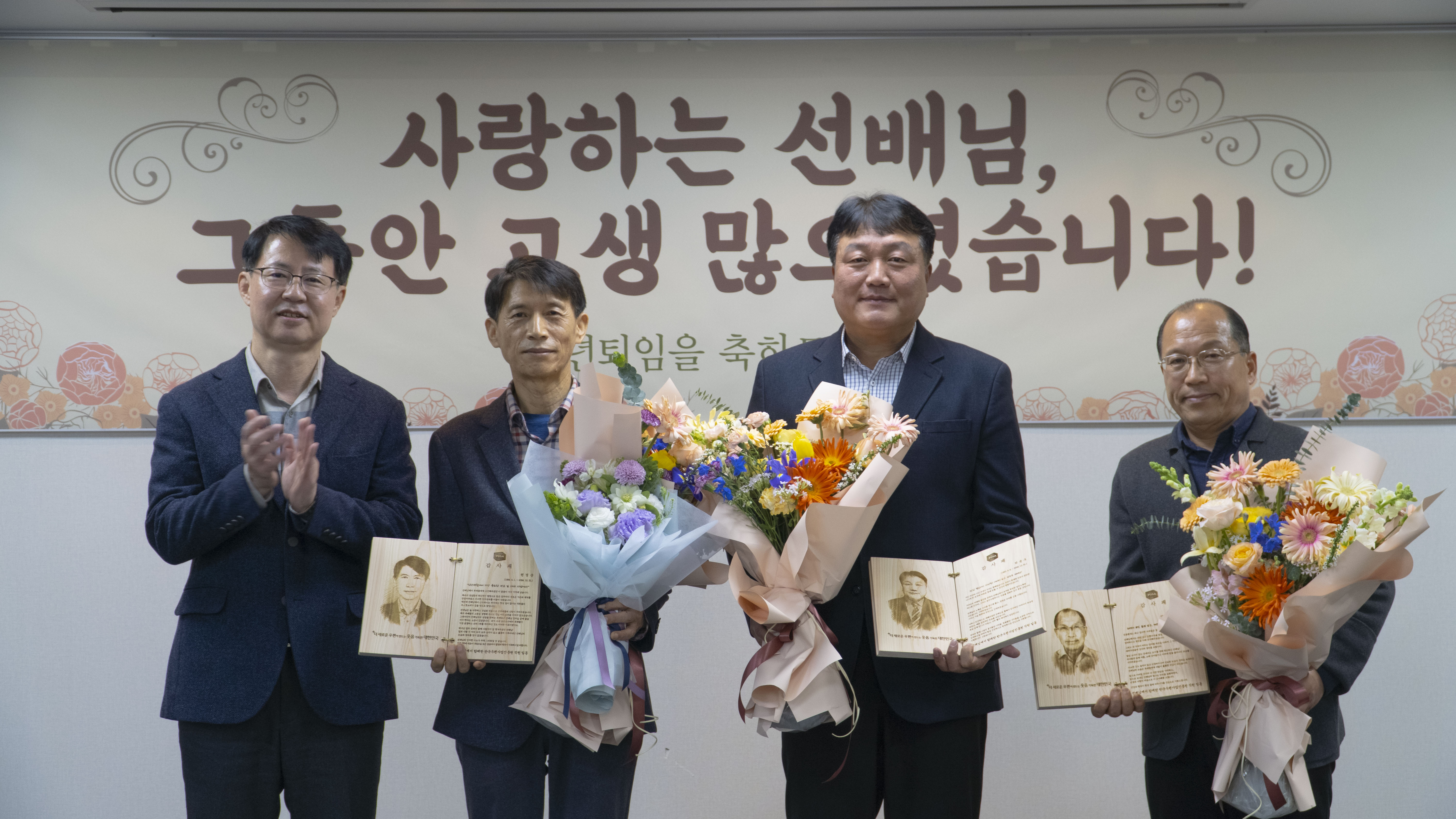 감사패와 꽃다발을 들고 사진을 찍는 모습
