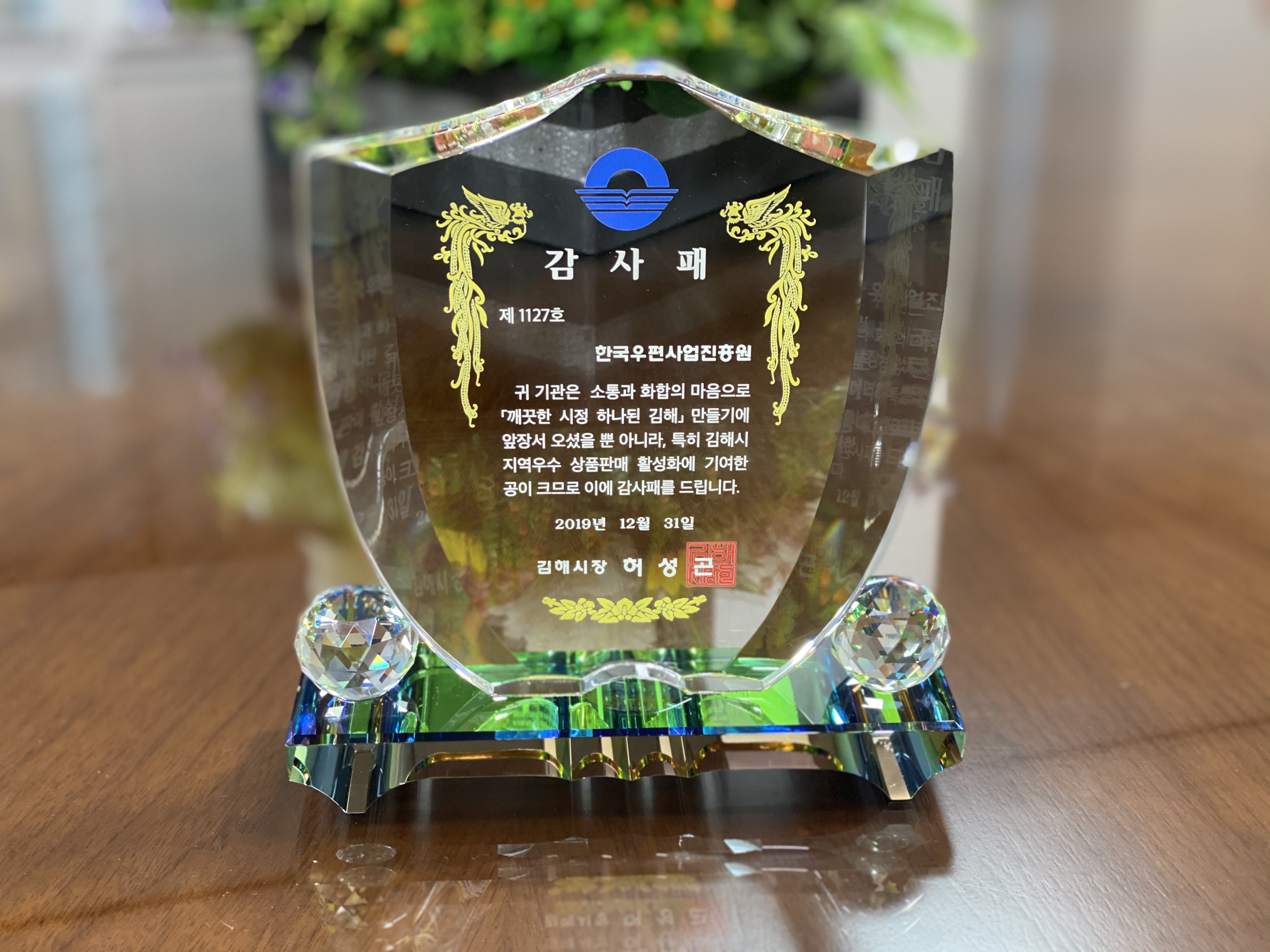 감사패 제1127호 한국우편사업진흥원 귀 기관은 소통과 화합의 마음으로 깨끗한 시정 하나된 김해 만들기에 앞장서 오셨을 뿐 아니라, 특히 김해시 지역우수 상품판매 활성화에 기여한 공이 크므로 이에 감사패를 드립니다. 2019년 12월 31일 김해시장 허송곤