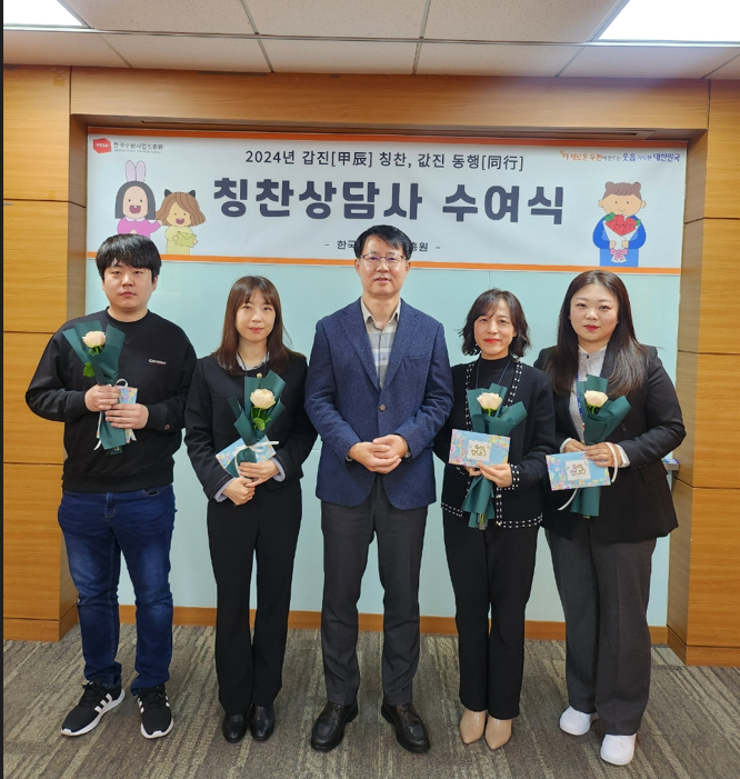 칭찬상담사 수여자들이 편지와 꽃을 들고 단체사진을 찍는 모습