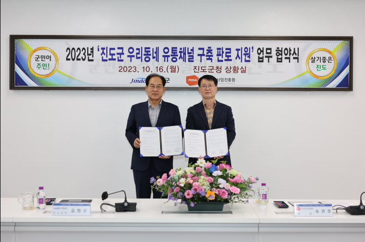 진도군 우리동네 유통채널 구축 판로 지원 업무 협약서를 들고 사진을 찍는 모습