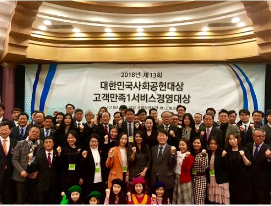 2018년 제 13회 대한민국사회공헌대상 고객만족1서비스 경영대상 현수막 앞에서 임정수원장과 사람들이 파이팅하며 기념촬영
