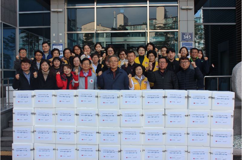 김치를 담근 후 포장되어 있는 50포기의 김치와 함께 참여한 사람들과 단체사진